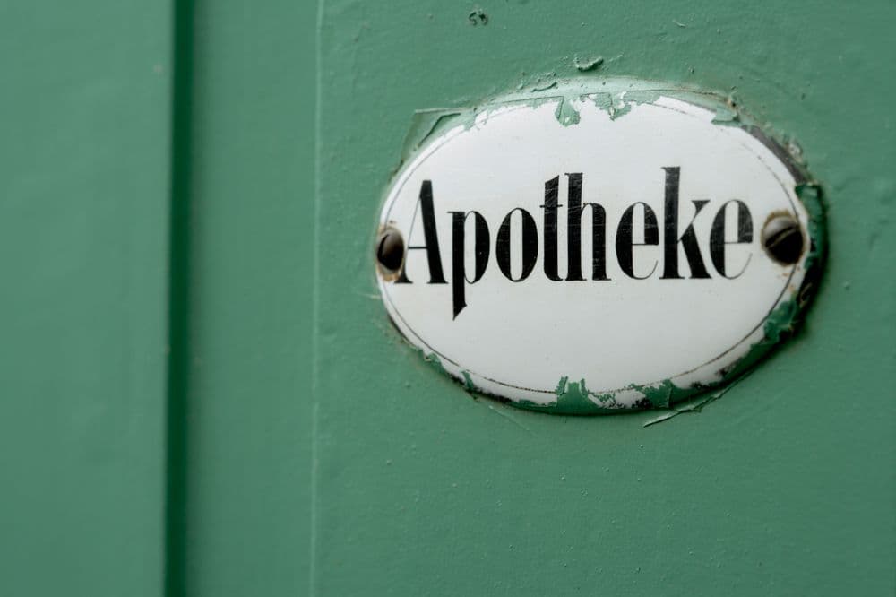 Emailleschild „Apotheke“ an einer grünen Tür